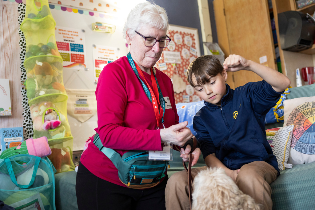 Linda Buchs-Hammonds, left, shows fifth grader Miles how to ask Sage, a therapy dog, to sit at Valley View Elementary School on April 29, 2026, in Columbia Heights, Minn. (Ellen Schmidt/MinnPost via AP)
