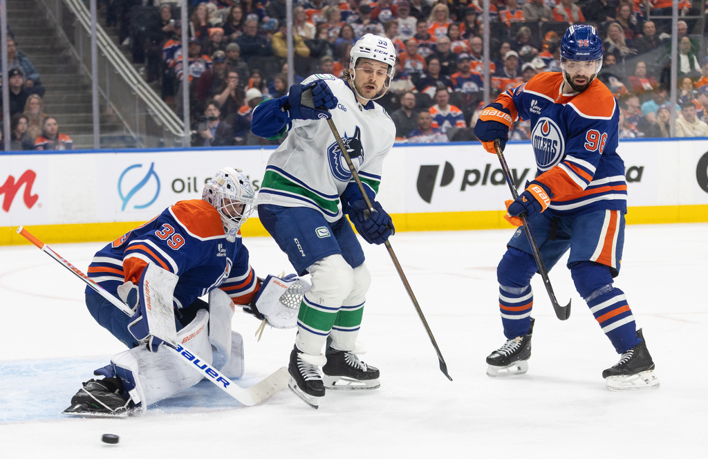 Vancouver Canucks' Teddy Blueger (53) screens Edmonton Oilers goalie Connor Ingram (39) as he makes the save and Jake Walman (96) defends during the third period of an NHL game, in Edmonton, Thursday, April 16, 2026. (Jason Franson/The Canadian Press via AP)