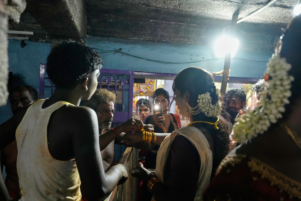 A priest ties a sacred thread on the hand of a transgender participant symbolically marrying the Hindu god Aravan during the Koovagam festival in Kallakurichi district in the southern Indian state of Tamil Nadu, Tuesday, April 28, 2026. (AP Photo/Mahesh Kumar A.)