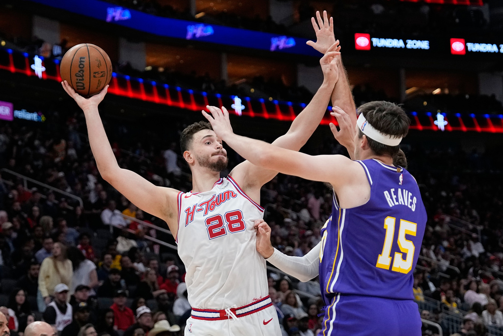 Houston Rockets' Alperen Sengun (28) looks to pass the ball as Los Angeles Lakers' Austin Reaves (15) and Luke Kennard defend during the first half of an NBA basketball game Wednesday, March 18, 2026, in Houston. (AP Photo/David J. Phillip)