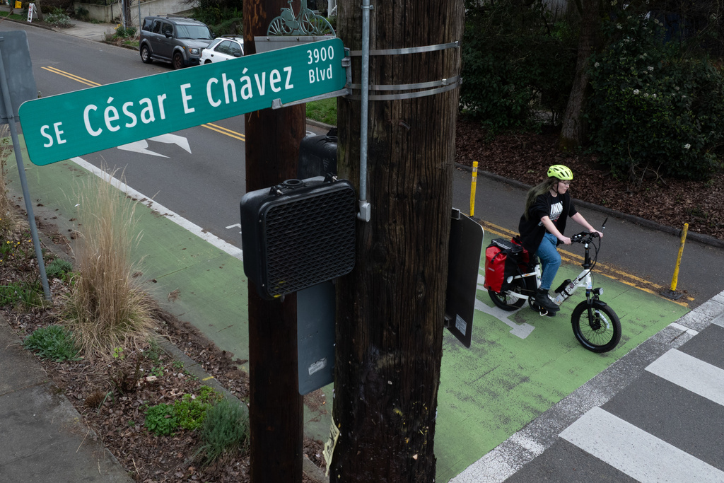 A bicyclist waits to cross SE César E Chávez Boulevard on Wednesday, March 18, 2026, in Portland, Ore. (AP Photo/Jenny Kane)