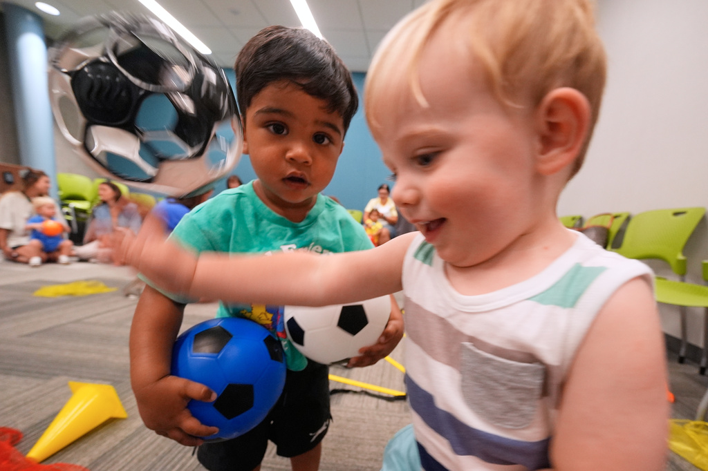 One-year-olds Ryder Greene, right, and Salaar Kahn play with a soccer balls at a program introducing toddlers to the sport ahead of the World Cup soccer tournament Thursday, June 4, 2026, in Lenexa, Kan. (AP Photo/Charlie Riedel)
