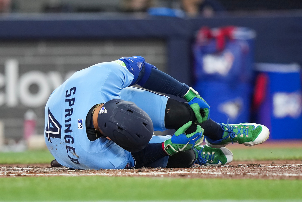 Toronto Blue Jays designated hitter George Springer falls to the ground after taking a foul ball off his foot while playing against the Minnesota Twins during third-inning baseball game action in Toronto, Saturday, April 11, 2026. (Nathan Denette/The Canadian Press via AP)