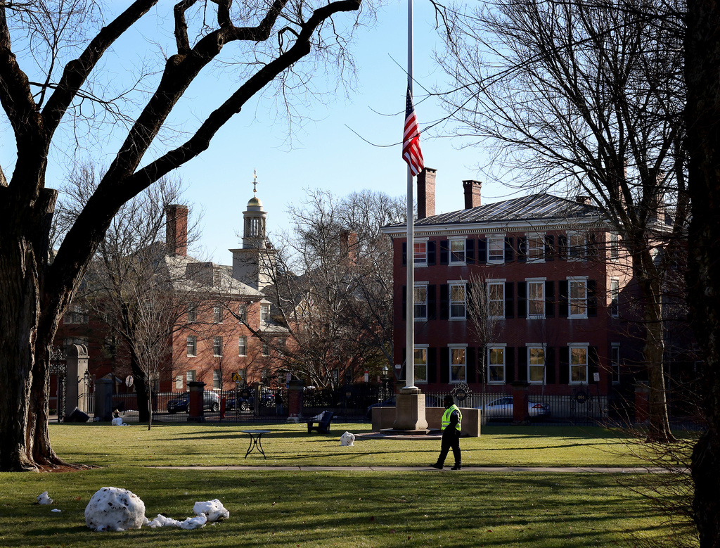 A security guard walks past a flag at half-staff on the main green of Brown University in Providence, RI, Thursday, Dec. 18, 2025, (AP Photo/ Mark Stockwell)