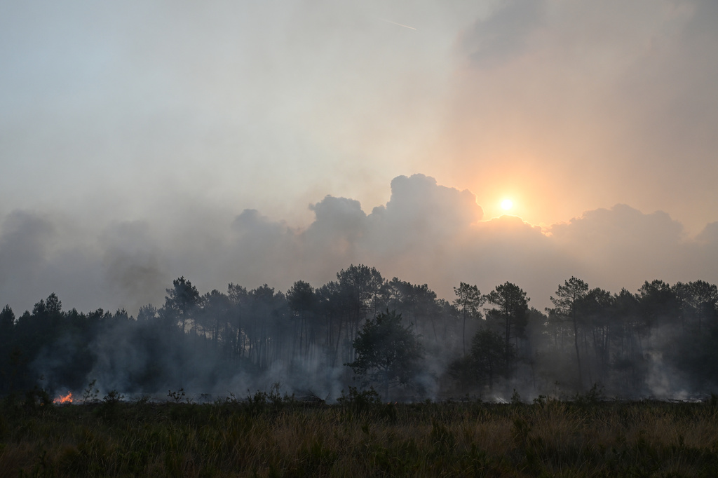 The rising sun appears through smoke from burning wildfires near Marcheprime, outside Bordeaux, France, Sunday, July 26, 2026. (AP Photo/Emma Da Silva)