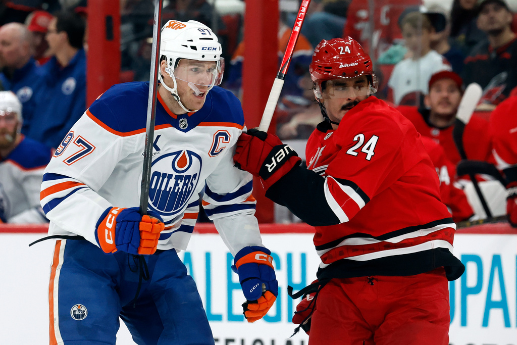 Carolina Hurricanes' Seth Jarvis (24) and Edmonton Oilers' Connor McDavid (97) chase the puck during the second period of an NHL hockey game in Raleigh, N.C., Saturday, Nov. 15, 2025. (AP Photo/Karl DeBlaker)
