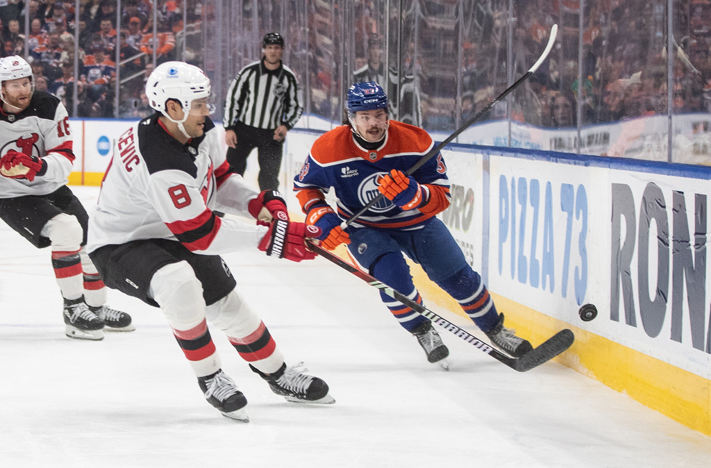 New Jersey Devils' Johnathan Kovacevic (8) and Edmonton Oilers' Isaac Howard (53) battle for the puck during the second period of an NHL hockey game in Edmonton on Tuesday, Jan. 20, 2026. (Jason Franson/The Canadian Press via AP)