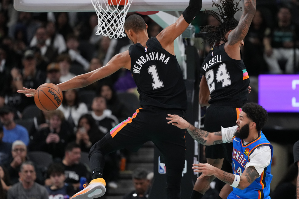 Oklahoma City Thunder guard Kenrich Williams (34) tries to move the ball past San Antonio Spurs forward Victor Wembanyama (1) and guard Devin Vassell (24) during the second half of an NBA basketball game in San Antonio, Wednesday, February. 4, 2026. (AP Photo/Eric Gay)
