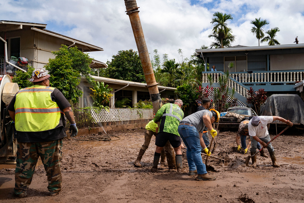 Volunteers assist in clearing mud using heavy equipment in a flooded residential neighborhood, Tuesday, March 24, 2026, in Waialua, Hawaii. (AP Photo/Mengshin Lin)