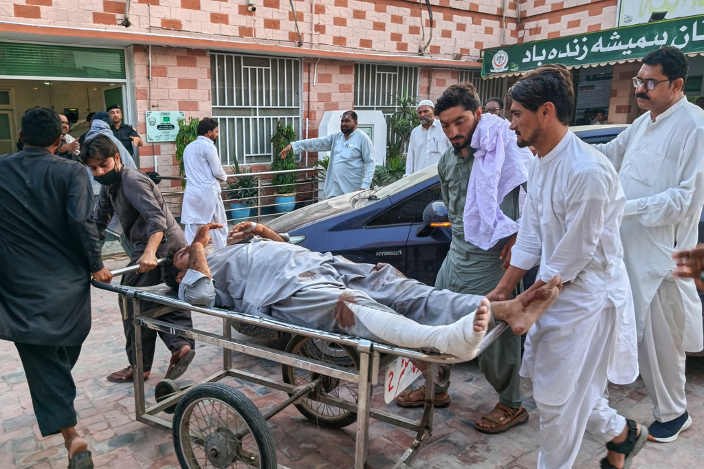 In this photo taken with a smartphone, volunteers transport an injured victim of a suicide attack on a roadside police checkpoint upon his arrival at a hospital in Dera Ismail Khan, Pakistan, Saturday, Sept. 26, 2026. (AP Photo/Kashif Naveed)