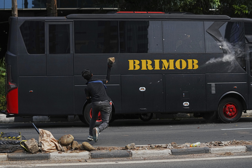 A student throws a rock at a police bus during a protest against lavish allowances given to parliament members, in Jakarta, Indonesia, Monday, Aug. 25, 2025. (AP Photo/Achmad Ibrahim)