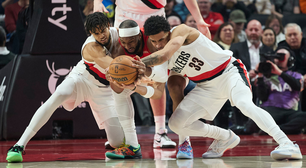 Houston Rockets guard Josh Okogie, center, fights for the ball with Portland Trail Blazers forward Rayan Rupert, left, and forward Toumani Camara during the first half of an NBA basketball game in Portland, Ore., Wednesday, Jan. 7, 2026. (AP Photo/Craig Mitchelldyer)