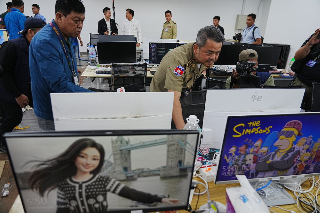 Bun Sosekha, Deputy Commissioner in charge of Security Unit, Phnom Penh Municipal Police, checks equipment confiscated in a raid by Cambodian police at a scam center in Phnom Penh, Cambodia, Wednesday, March 11, 2026. (AP Photo/Heng Sinith)