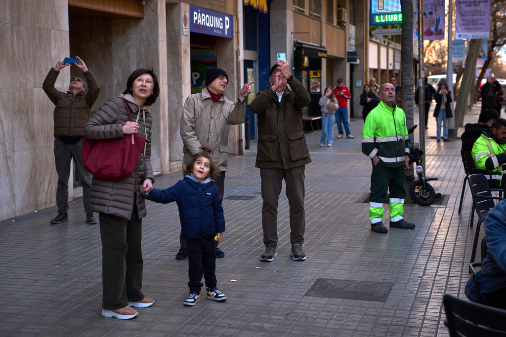 People watch as a crane lifts the upper arm of the cross onto the Tower of Jesus Christ at the Sagrada Familia in Barcelona, Spain, Friday, Feb. 20, 2026, reaching the basilica's maximum height of 172.5 meters (566 feet). (AP Photo/Emilio Morenatti)