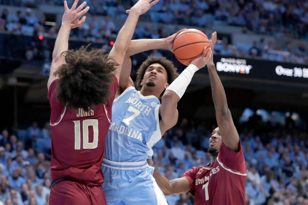 North Carolina guard Seth Trimble (7) drives between Florida State guard Lajae Jones (10) and forward Chauncey Wiggins, right, during the first half of an NCAA college basketball game Tuesday, Dec. 30, 2025, in Chapel Hill, N.C. (AP Photo/Chris Seward)