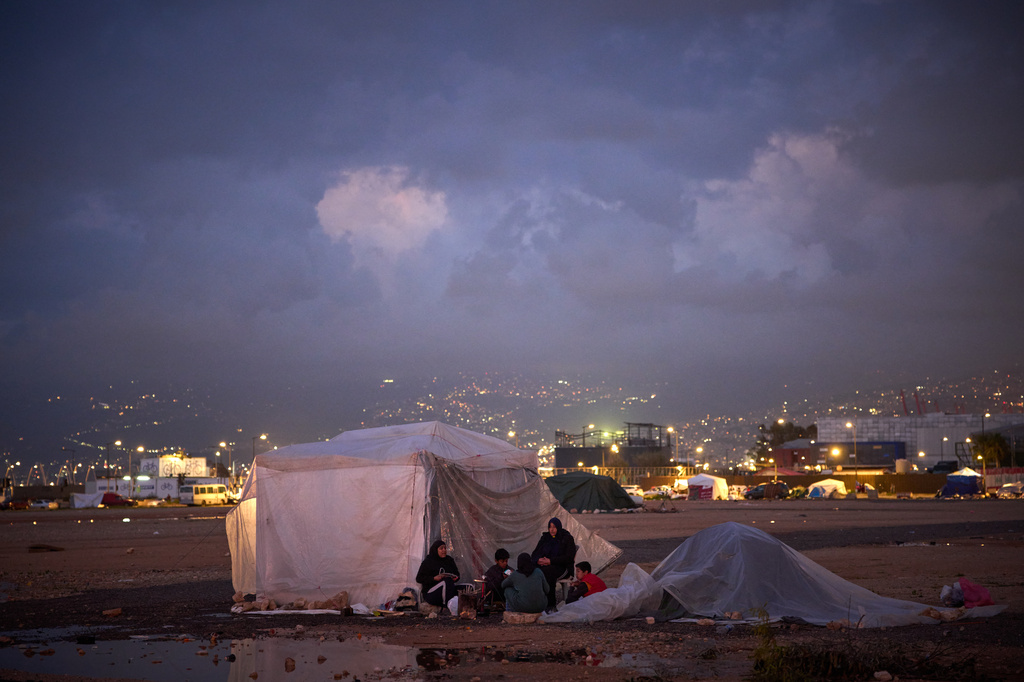 Members of a family who fled Israeli strikes in southern Lebanon, sit outside a tent used as a shelter in Beirut, Lebanon, Friday, March 27, 2026. (AP Photo/Emilio Morenatti)