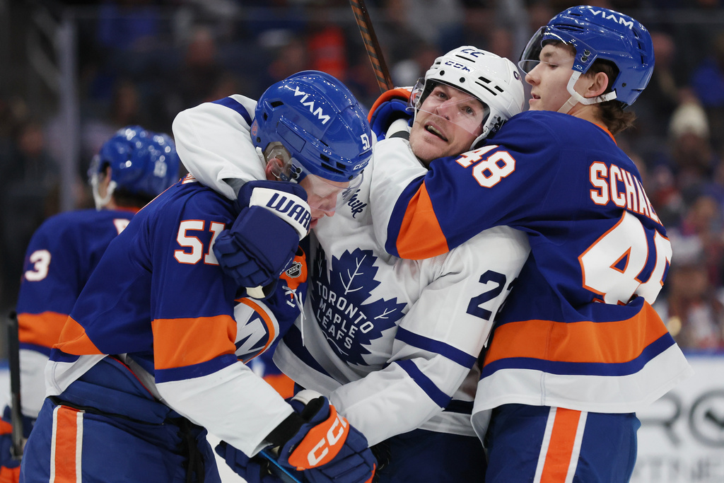 New York Islanders' Emil Heineman and Matthew Schaefer (48) hold back Toronto Maple Leafs' Jake McCabe, center, during a fight in the first period of an NHL hockey game, Saturday, Jan. 3, 2026, in Elmont, N.Y. (AP Photo/Heather Khalifa)