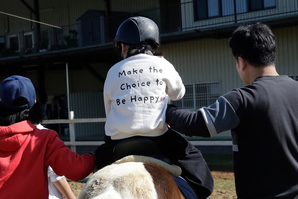 A girl is supported by her father and a physical therapist as she rides a horse during an equine-assisted therapy course at the Therapeutic Riding Centre in Taoyuan in northern Taiwan on Thursday, Jan. 29, 2026. (AP Photo/Chiang Ying-ying)