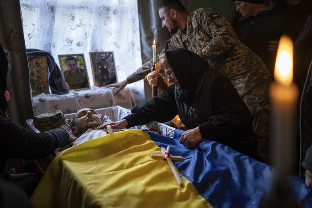 FILE - The mother of Ukrainian army officer Vasyl Medviychuk touches her son during his funeral ceremony in the Carpathian mountains in Krasnyk village, Ukraine, Dec. 29, 2023. (AP Photo/Evgeniy Maloletka, File)