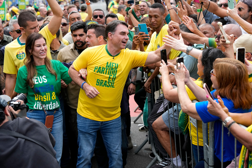 Opposition presidential candidate Flavio Bolsonaro and his wife, Fernanda Bolsonaro, greet supporters as they arrive for a presidential election campaign rally in Rio de Janeiro, Brazil, Sunday, Aug. 16, 2026. (AP Photo/Silvia Izquierdo)