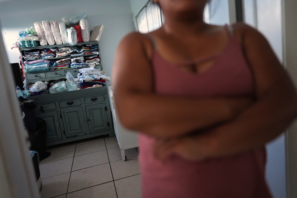 Diapers and clothes fill the shelves of the apartment in South Florida where Guatemalan migrant Amavilia, 31, front, lives with her two children and a roommate, after her partner Edgar was detained days after their son's birth and deported to Guatemala, Wednesday, Oct. 8, 2025. (AP Photo/Rebecca Blackwell)