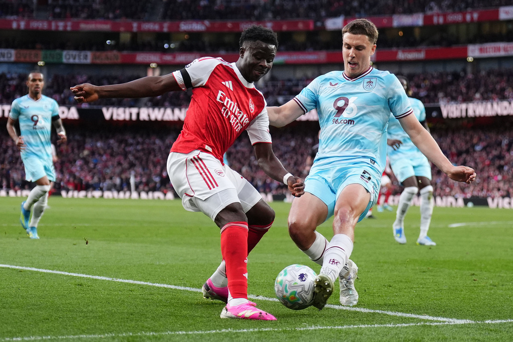 Arsenal's Bukayo Saka, left, and Burnley's Maxime Esteve battle for the ball during the English Premier League soccer match between Arsenal and Burnley in London, Monday May 18, 2026. (John Walton/PA via AP)