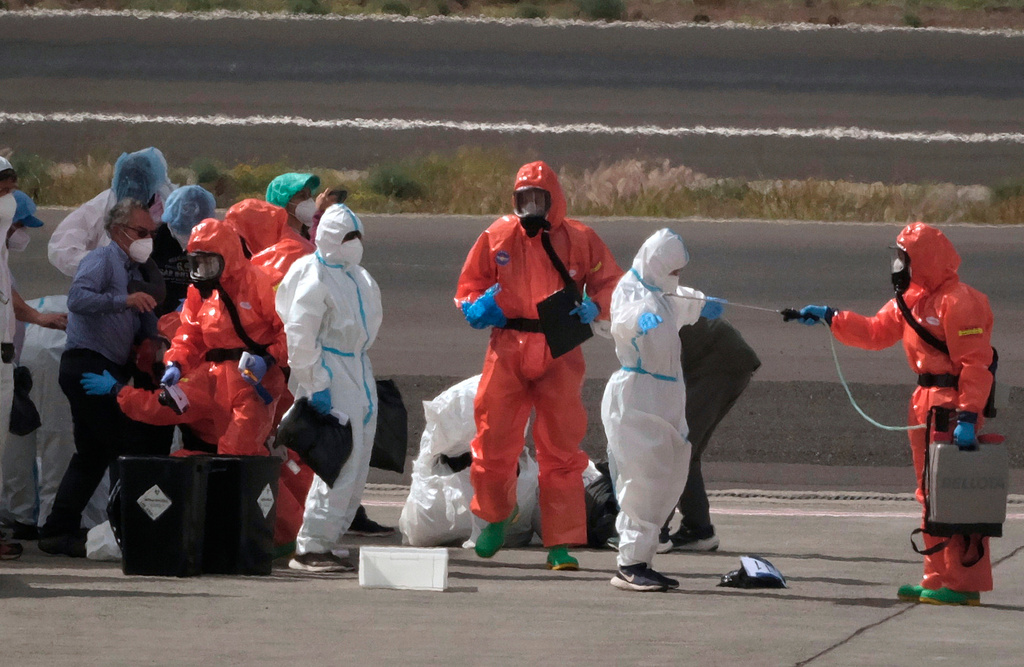 FILE - Passengers are sprayed with disinfectant by Spanish government officials before boarding a plane after disembarking from the hantavirus-stricken cruise ship MV Hondius at Tenerife airport in the Canary Islands, Spain, Sunday, May 10, 2026. (AP Photo/Arturo Rodriguez,File)