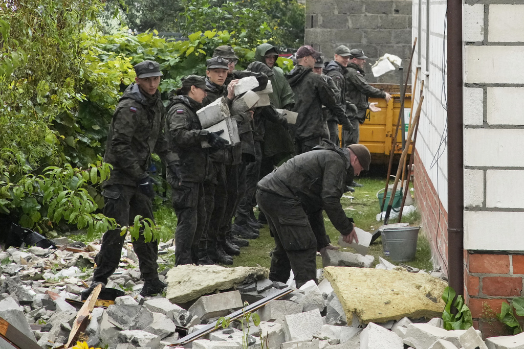 Territorial defense officers clean up debris from the destroyed roof of a house, after multiple Russian drones struck, in Wyryki near Lublin, Poland, Thursday, Sept. 11, 2025. (AP Photo/Czarek Sokolowski)