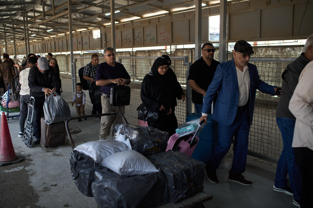 Carrying their belongings, people who arrived from Iran cross the Shalamcheh border crossing between Iran and Iraq, near Basra, Iraq, Sunday, March 29, 2026. (AP Photo/Leo Correa)