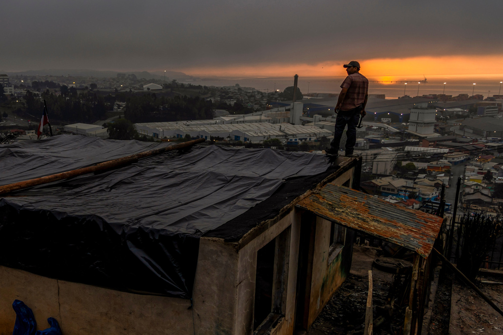 Jonathan Escalona stands over his house damaged by wildfires in Lirquen, Chile, Tuesday, Jan. 20, 2026. (AP Photo/Javier Torres)