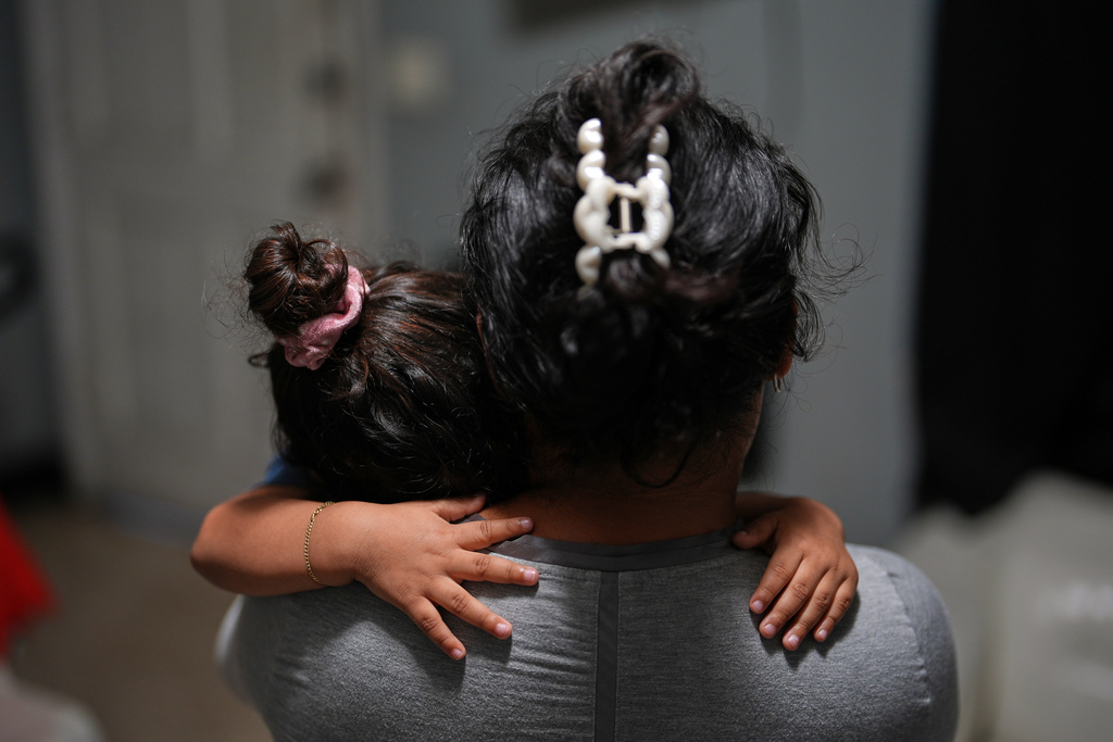 Pregnant asylum-seeker Yaoska, 32, comforts her two-year-old son who was not feeling well, inside the Miami-area motel room where she and her children are living after her husband was deported to Nicaragua, Thursday, Nov. 13, 2025. (AP Photo/Rebecca Blackwell)