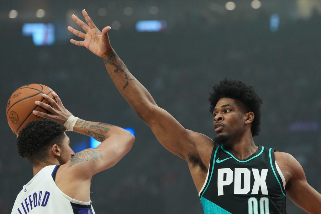 Sacramento Kings guard Nique Clifford looks to pass around Portland Trail Blazers guard Scoot Henderson (00) during the first half of an NBA basketball game Sunday, April 12, 2026, in Portland, Ore. (AP Photo/Jenny Kane)