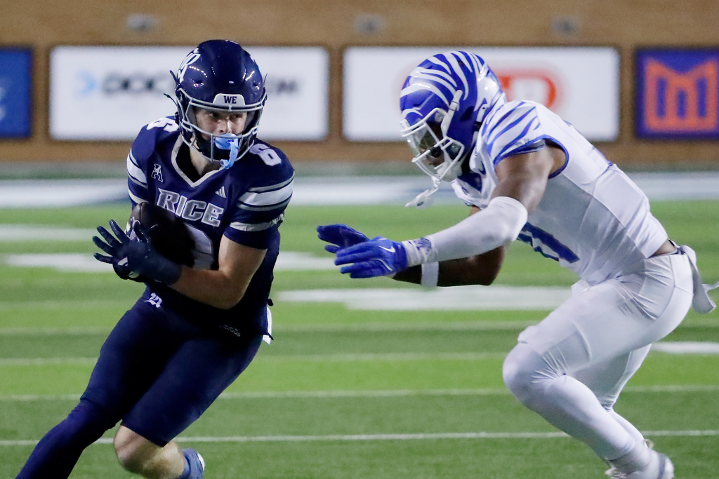 Rice quarterback Lucas Scheerhorn, left, makes a gain before contact with Memphis linebacker Demarco Ward, right, during the first half of an NCAA college football game Friday, Oct. 31, 2025, in Houston. (AP Photo/Michael Wyke)