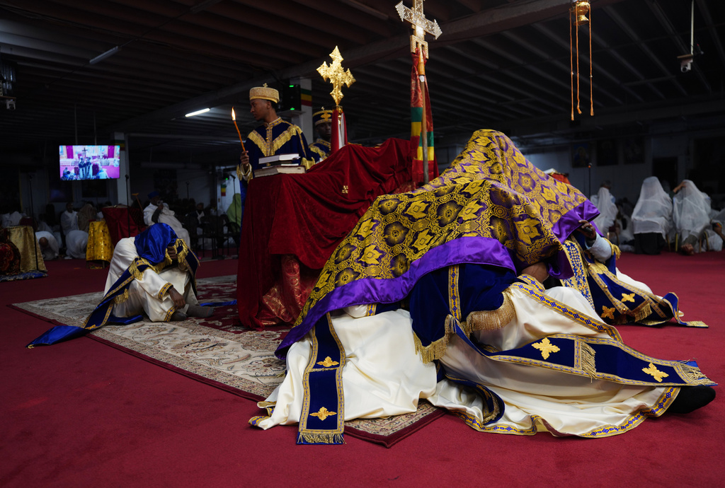 During Good Friday, priests, or "kesis," chant together as they huddle under a dark purple and gold garment, to represent Christ triumphing over evil and providing salvation, at Re'ese Adbarat Debre Selam Kidist Mariam Church, an Ethiopian Orthodox Tewahedo church, in Washington, Friday, April 10, 2026. (AP Photo/Jessie Wardarski)