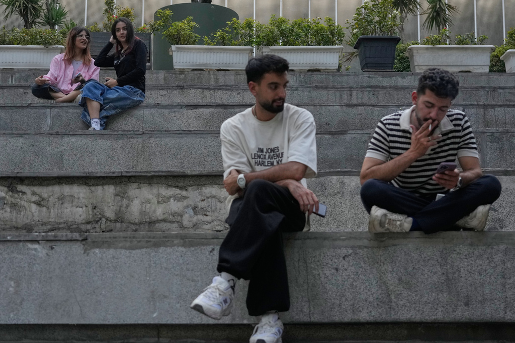 Youths spend an afternoon sitting on the steps outside a shopping mall in northern Tehran, Iran, Thursday, Aug. 13, 2026. (AP Photo/Vahid Salemi)