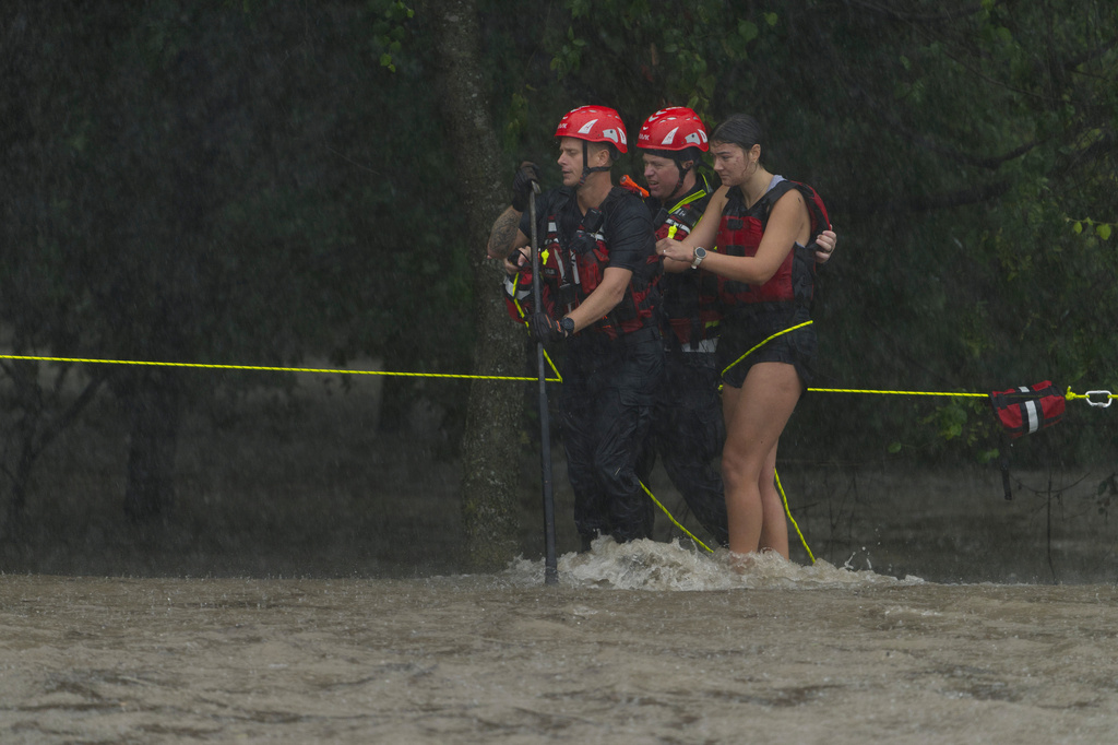 Members of the Boerne Fire Dept. rescue a woman from flood waters on Wednesday, July 15, 2026, in Boerne, Texas. (AP Photo/Darren Abate)