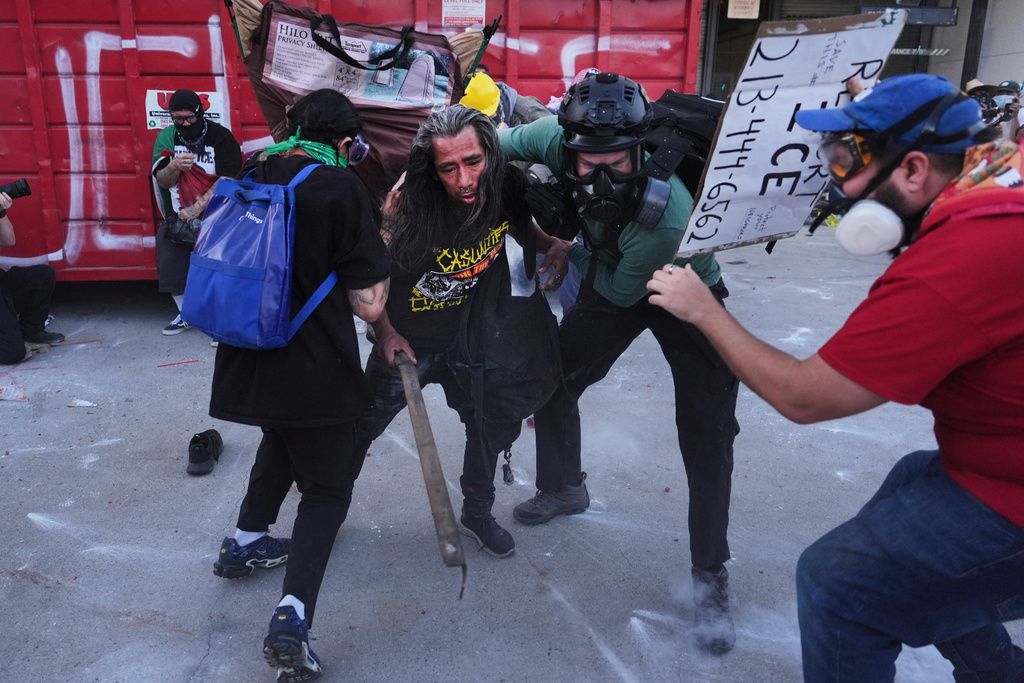 Protesters take cover from tear gas fired by federal police during clashes at the Metropolitan Detention Center in downtown Los Angeles on Friday, Jan. 30,2026. (AP Photo/Jae C. Hong)