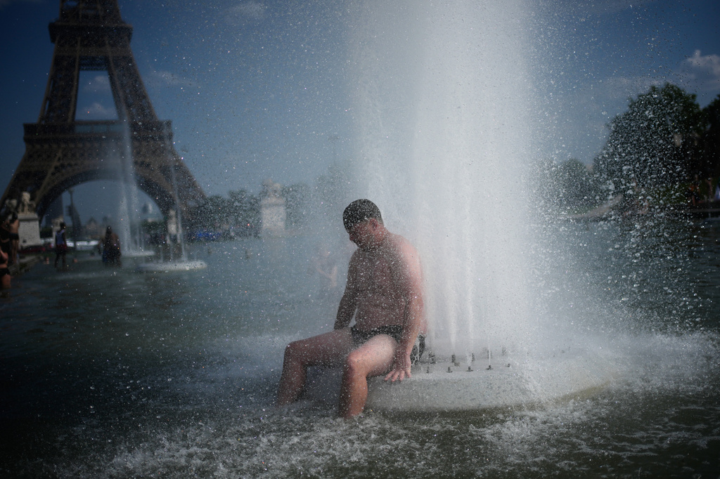 A person cools off at Trocadero fountain near the Eiffel Tower during a heat wave in Paris, Wednesday, June 24, 2026. (AP Photo/Christophe Ena)