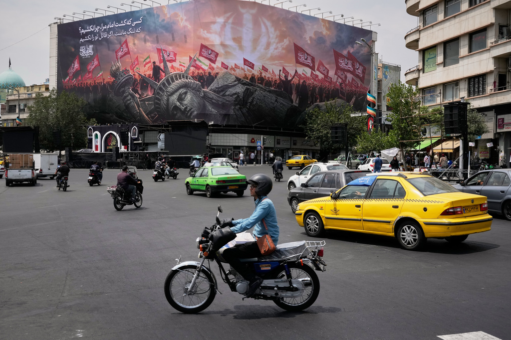 Vehicles travel past a billboard depicting a fallen Statue of Liberty and crowds carrying Iranian and Shiite flags at Revolution Square in Tehran, Iran, Monday, Aug. 3, 2026. (AP Photo/Vahid Salemi)