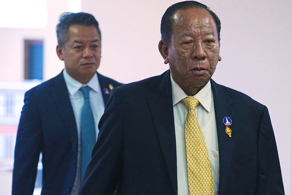 Cambodian lawmaker Tea Banh, right, walks together with his son, Deputy Prime Minister and Minister of National Defense Tea Seiha, left, before the session on the draft law on amending the law on nationality at the National Assembly in Phnom Penh Cambodia, Monday, Aug. 25, 2025. (AP Photo/Heng Sinith)