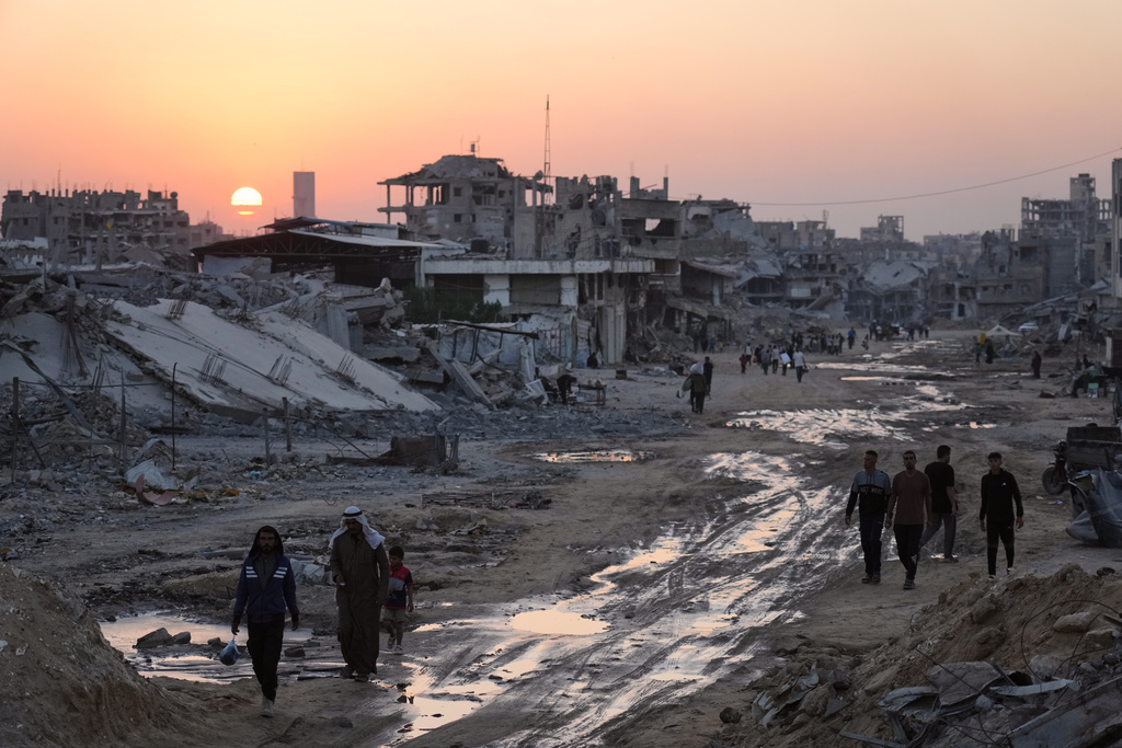 Palestinians walk among destroyed buildings in Khan Younis, southern Gaza Strip, Sunday, Nov. 2, 2025. (AP Photo/Jehad Alshrafi)