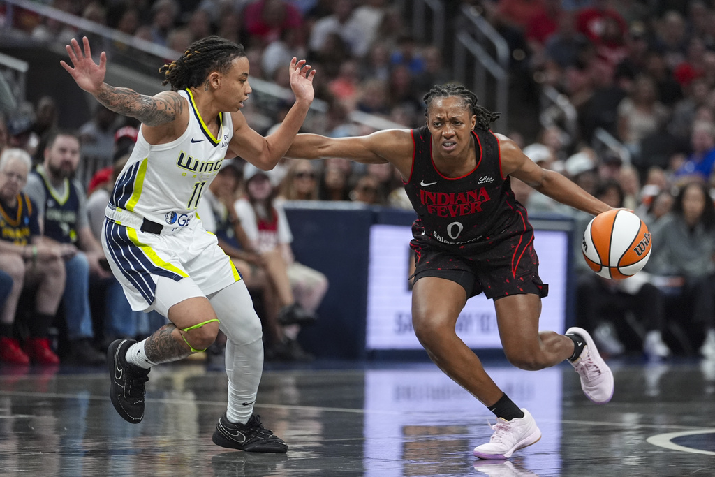 Indiana Fever guard Kelsey Mitchell (0) drives on Dallas Wings guard JJ Quinerly (11) in the second half of a WNBA basketball game in Indianapolis, Tuesday, Aug. 12, 2025. (AP Photo/Michael Conroy)