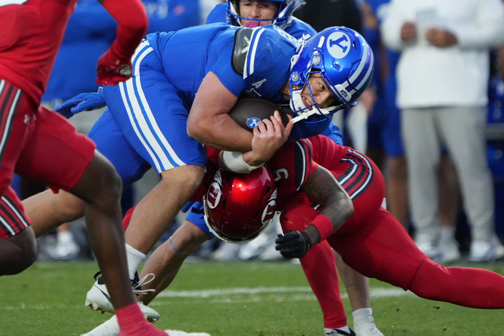 BYU quarterback Bear Bachmeier, left, is hit by Utah safety Tao Johnson (5) during the first half of an NCAA college football game Saturday, Oct. 18, 2025, in Provo, Utah. (AP Photo/George Frey)