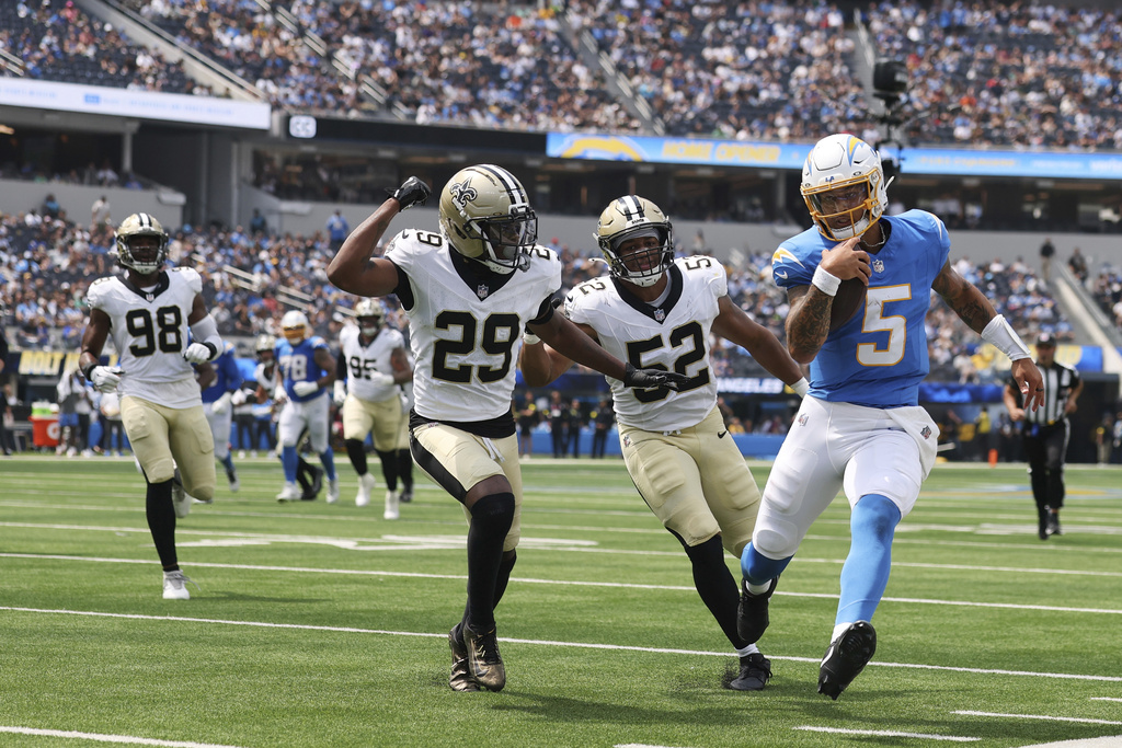 Los Angeles Chargers quarterback Trey Lance (5) runs for a first down past New Orleans Saints linebacker D'Marco Jackson (52) and cornerback Quincy Riley (29) during the first half of a preseason NFL football game Sunday, Aug. 10, 2025, in Inglewood, Calif. (AP Photo/Eric Thayer)