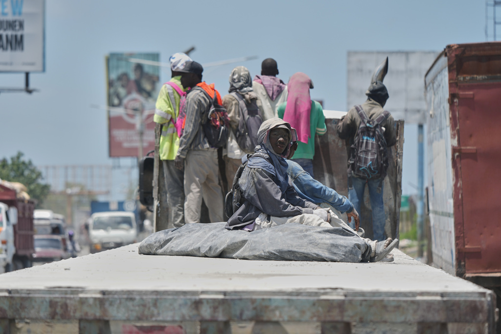 Workers ride in a cargo truck transporting cement in Port-au-Prince, Haiti, Tuesday, April 7, 2026. (AP Photo/Odelyn Joseph)