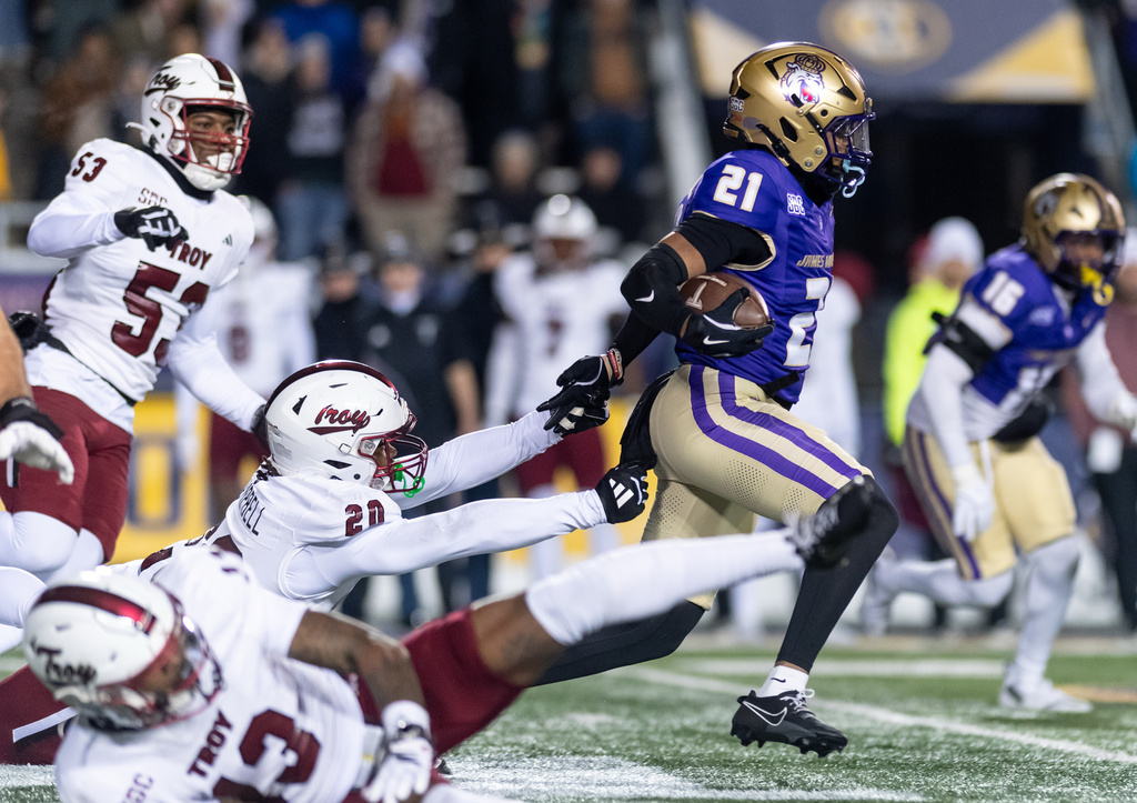 James Madison running back Jackson McCarter (21) escapes from Troy linebacker Keyshawn Campbell (20) during the first half of the Sun Belt championship NCAA college football game in Harrisonburg, Va., Friday, Dec. 5, 2025. (Daniel Lin/Daily News-Record Via AP)