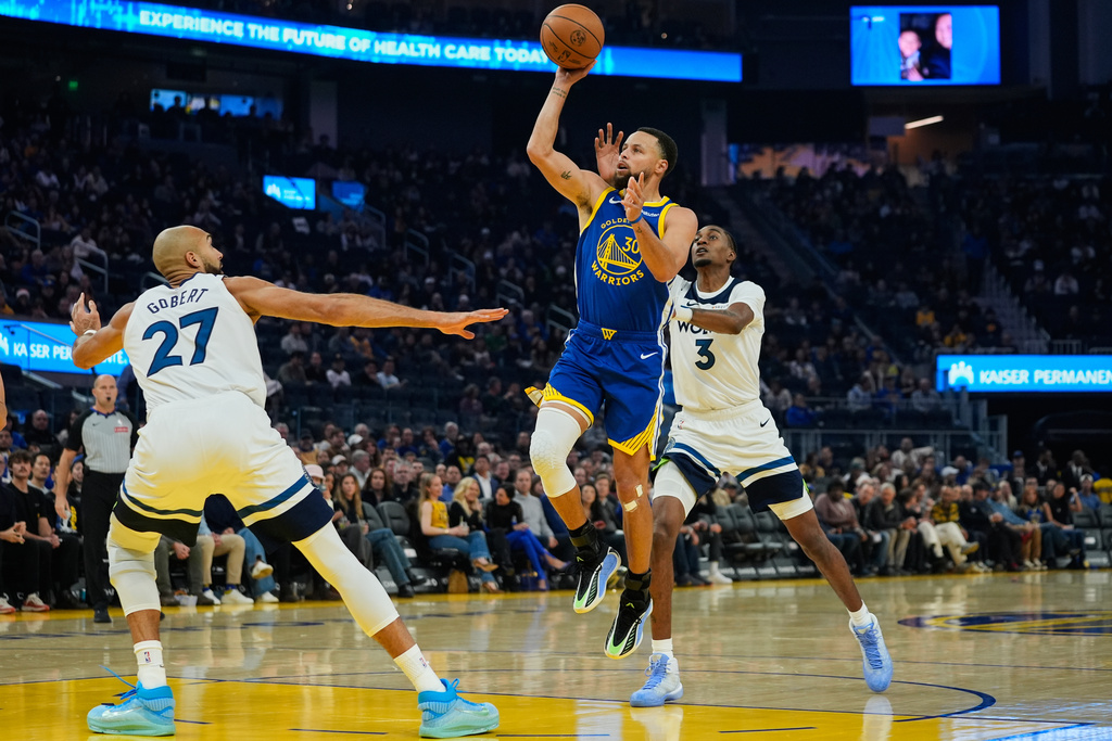 Golden State Warriors guard Stephen Curry (30) shoots between Minnesota Timberwolves center Rudy Gobert (27) and forward Jaden McDaniels (3) during the first half of an NBA basketball game, Friday, Dec. 12, 2025, in San Francisco. (AP Photo/Godofredo A. Vásquez)