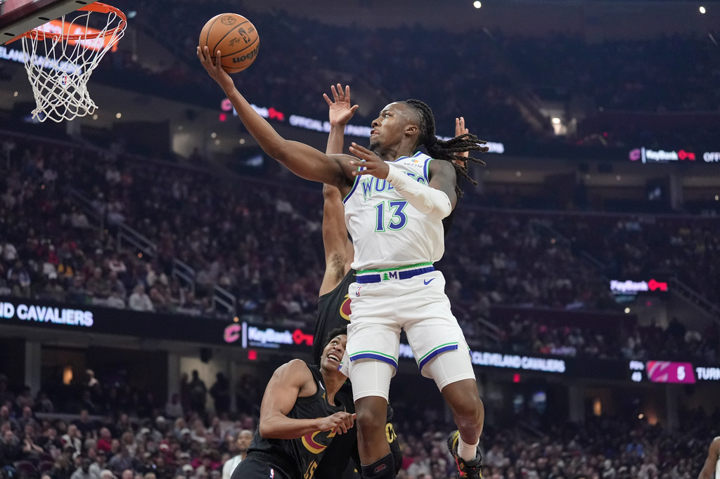 Minnesota Timberwolves guard Ayo Dosunmu (13) shoots in front of Cleveland Cavaliers guard Meleek Thomas, left, and guard Peyton Watson, rear, in the first half of an NBA basketball game, Monday, Oct. 26, 2026, in Cleveland. (AP Photo/Sue Ogrocki)