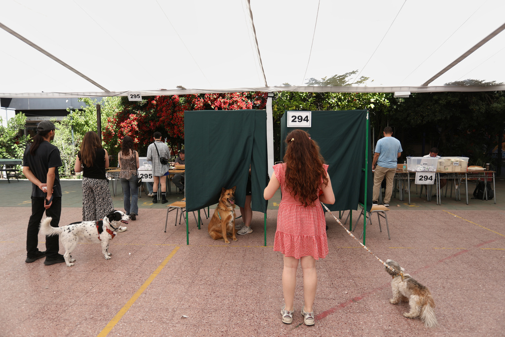 Voters and their dogs line up at a polling station during general elections in Santiago, Chile, Sunday, Nov. 16, 2025. (AP Photo/Cristobal Escobar)