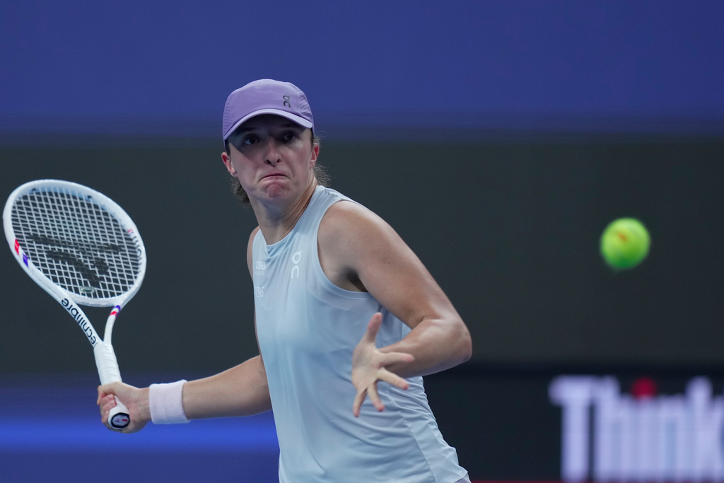 Iga Swiatek of Poland plays a forehand return to Emma Navarro, of the United States during the women's singles match for the China Open tennis tournament, in Beijing, China, Wednesday, Oct. 1, 2025. (AP Photo/Mahesh Kumar A.)